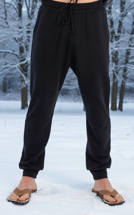 Black jogger pants worn by a person on a white background