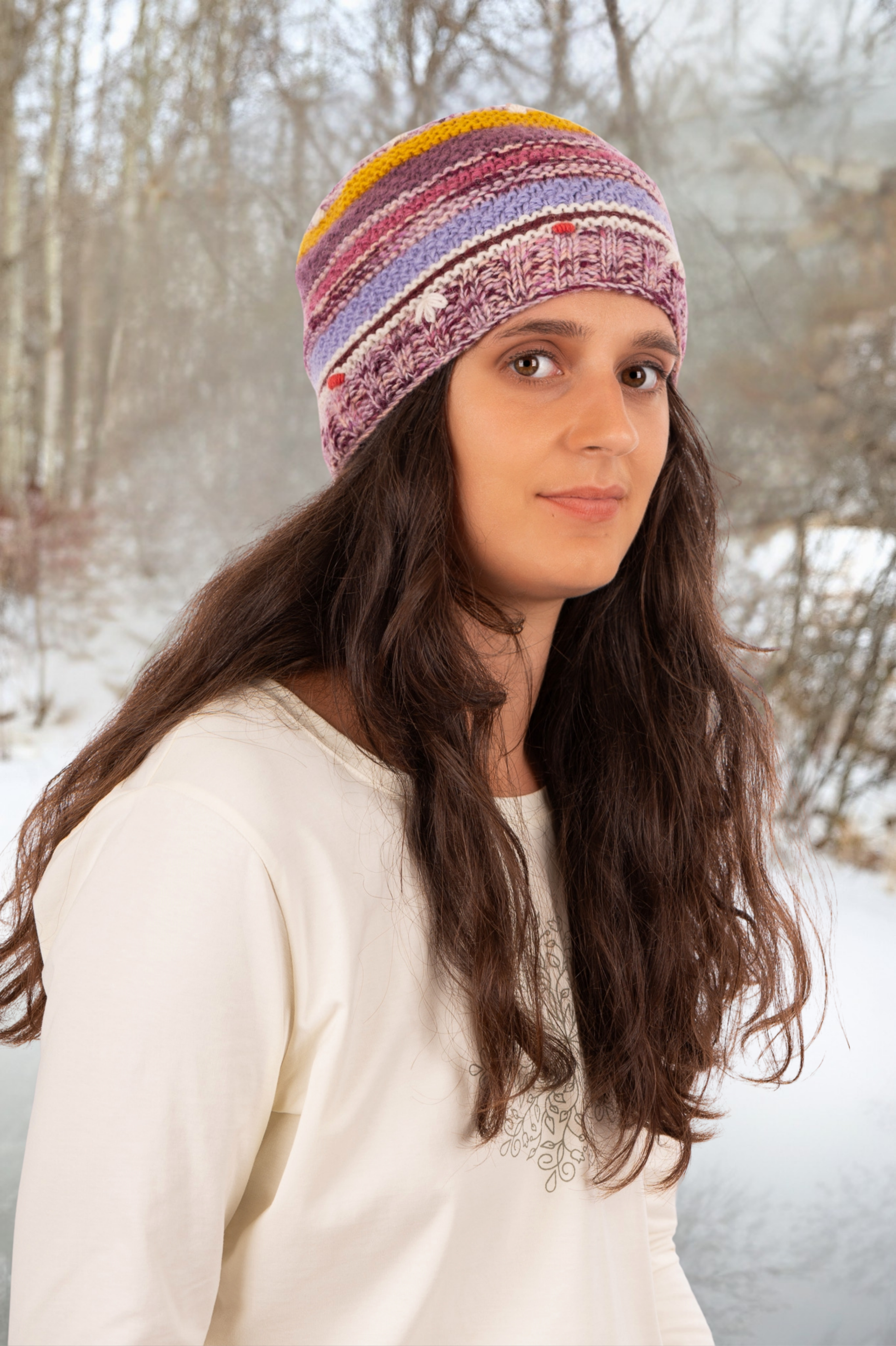 Woman wearing a colorful knitted hat in a snowy forest