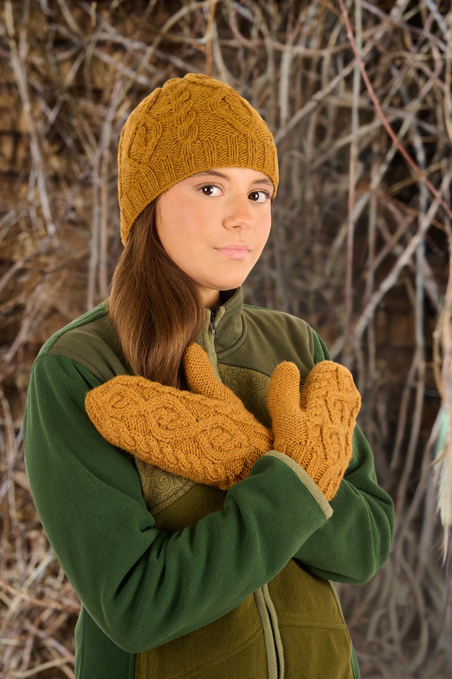Person wearing a yellow knitted hat and mittens against a natural background