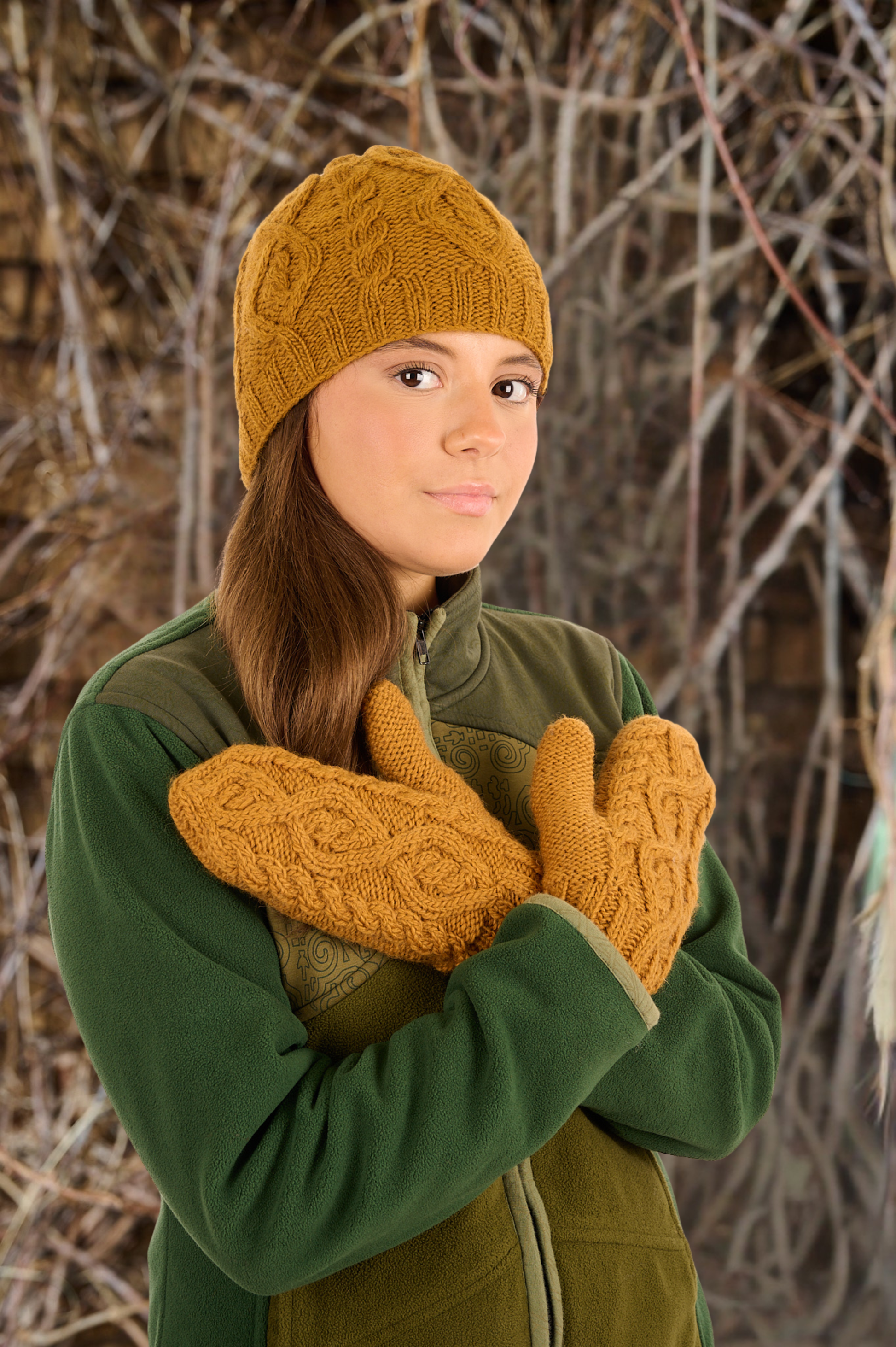 Person wearing a yellow knitted hat and mittens against a natural background